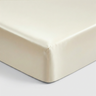 Close-up of an ivory silk fitted sheet's corner on a mattress