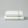 Stack of 2 folded ivory silk flat sheet with a silver piped design