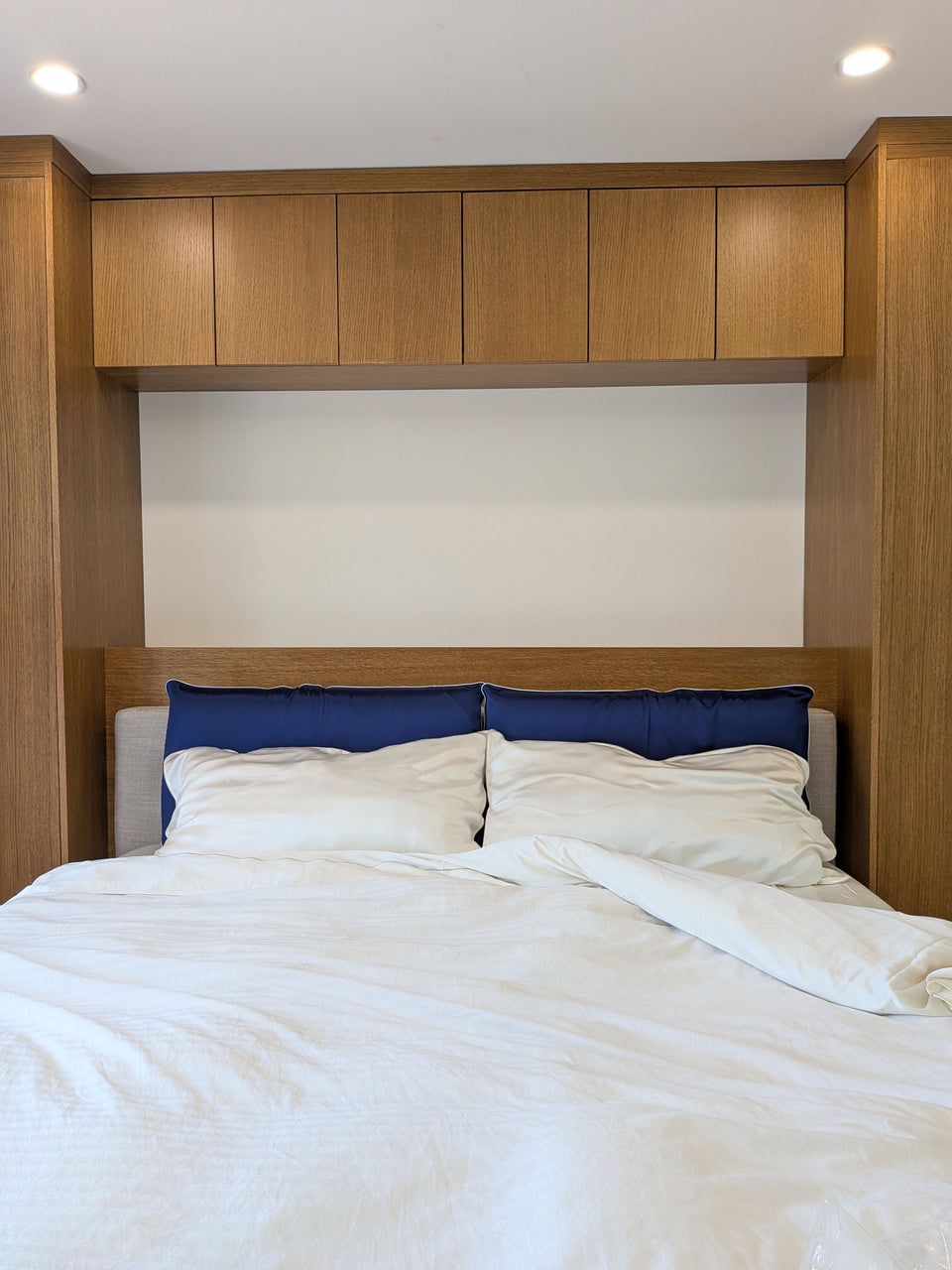 Navy silk pillows with white piping and an ivory-silver silk bed set in a wood-panelled bedroom