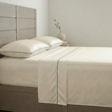 Ivory-silver silk sheet set on a made bed with matching pillows